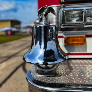 A detailed close-up of a shiny silver bell on a fire truck, Menominee, MI.