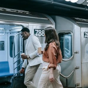Two colleagues walking on the New York subway platform, engaging in casual conversation.